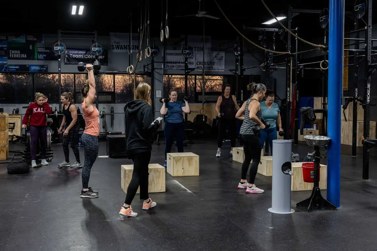 A group class working with dumbbells and plyo boxes on the CrossFit Milford floor